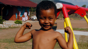 A boy standing outside flexing his muscles